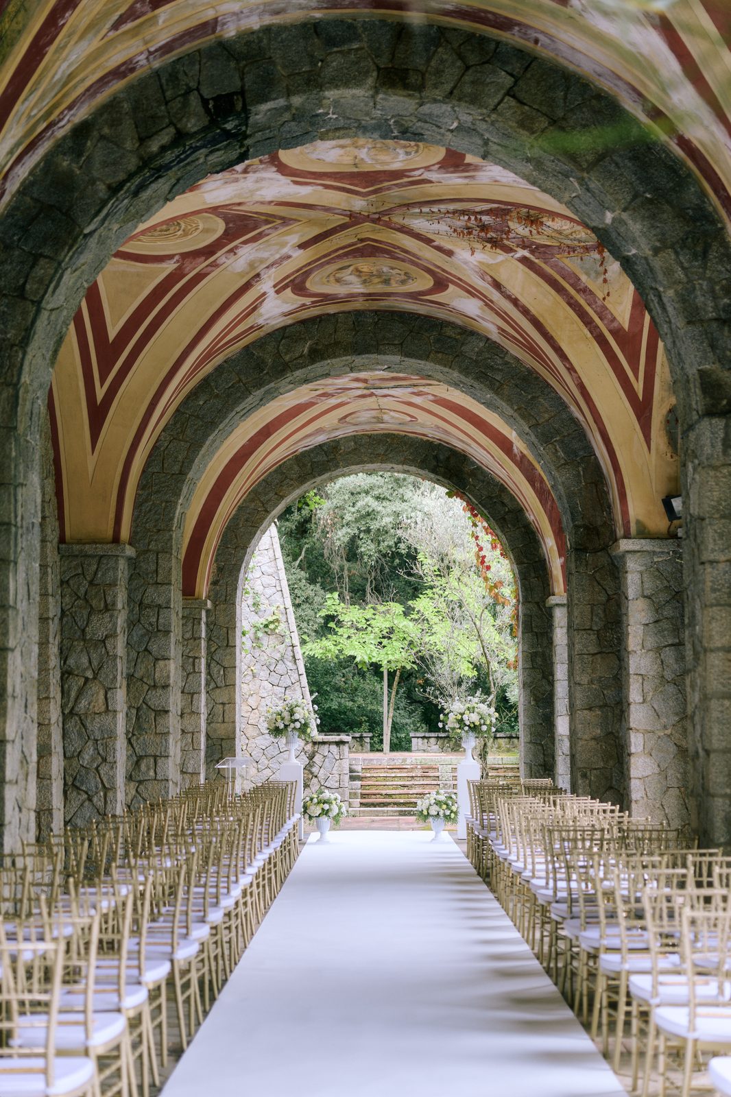 Ceremony setup — frescoed gallery with golden chairs