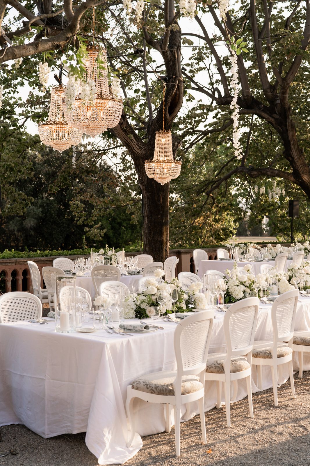 Reception detail — crystal chandeliers above white floral tables